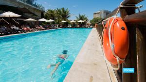 a man in the swimming pool at a resort at Vila Galé Salvador in Salvador