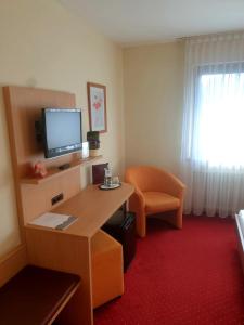 a hotel room with a desk with a television and a chair at Hotel Rössle in Freiberg am Neckar