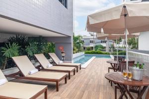 an outdoor patio with chairs and tables and a pool at Citi Hotel Premium Caruaru in Caruaru