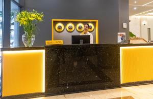 a woman standing at a yellow counter in a lobby at Kraal Hotel Vlore in Vlorë