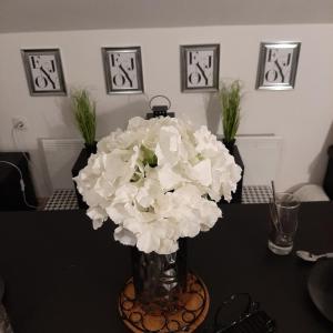 a vase filled with white flowers on a table at Apartment Mansarda in Maribor