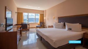 a hotel room with a large bed and a desk at Vila Galé Salvador in Salvador