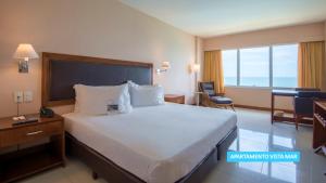 a hotel room with a large bed and a desk at Vila Galé Salvador in Salvador