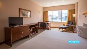 a hotel room with a bed and a desk and a television at Vila Galé Salvador in Salvador