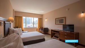 a hotel room with a bed and a desk and a television at Vila Galé Salvador in Salvador