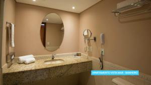 a bathroom with a sink with a mirror and a phone at Vila Galé Salvador in Salvador