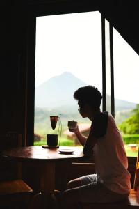 a woman sitting at a table with a cup of coffee at ARENAL ROCA LODGE in Fortuna