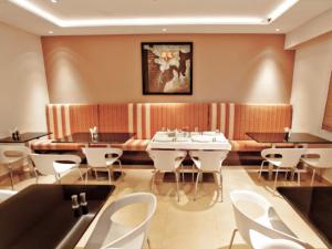 a restaurant with tables and chairs in a room at Mallige Residency in Hassan