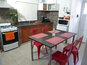 y cocina con mesa, sillas rojas y fogones. en LOS TATOS con cochera en Villa María