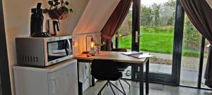 a kitchen with a microwave and a table with chairs at Hotelhuisje Warmenhuizen #C in Warmenhuizen +57 photos