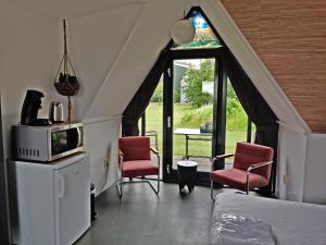 a bedroom with a bed and two chairs and a window at Hotelhuisje Warmenhuizen #C in Warmenhuizen