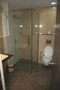 a bathroom with a glass shower and a toilet at Mallige Residency in Hassan