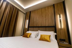 a bedroom with a large bed with two yellow pillows at Kraal Hotel Vlore in Vlorë