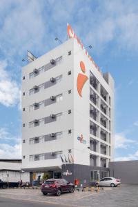 ein großes weißes Gebäude mit davor geparkt in der Unterkunft Citi Hotel Express Caruaru in Caruaru