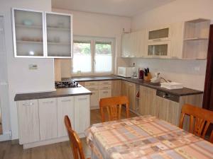 una cocina con armarios blancos y una mesa con sillas. en Apartment in Zamardi - Balaton 40474, en Zamárdi