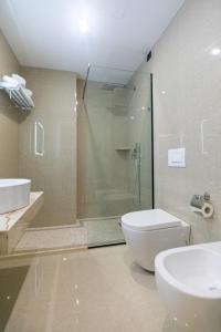 a bathroom with a shower and a toilet and a sink at Kraal Hotel Vlore in Vlorë
