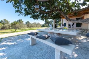 a white picnic table with pillows sitting under a tree at Villa Rogač in Sutivan