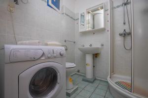 een badkamer met wasmachine en toilet bij Apartment in Dramalj 41384 in Klanfari