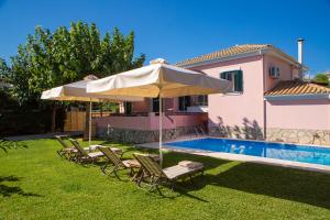 a pool with chairs and an umbrella next to a house at Anthemis Luxury Villas in Lygia