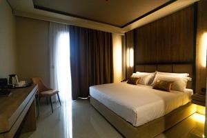 a bedroom with a bed and a desk and a window at Kraal Hotel Vlore in Vlorë
