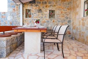 a table and chairs on a patio with a stone wall at Villa Elia in Dhrámia