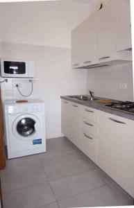 eine weiße Küche mit einer Waschmaschine und einer Waschmaschine in der Unterkunft Studio in Porto Santa Margherita 40176 in Porto Santa Margherita + 2 Fotos