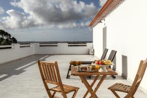 eine Terrasse mit Stühlen und einem Tisch mit einer Obstschale in der Unterkunft Pé no Campo Suites and Villa in Carvalhal