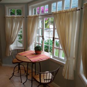 uma mesa e cadeiras num quarto com janelas em Casa Verde - Suíte 1 em Teresópolis