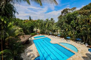 una imagen de una piscina en un complejo en Fabuloso flat 243 Amarílis 2 piscinas climatizadas, SKY 170 canais carregador veiculo elétrico Riviera de São Lourenço, Bertioga Apartamento Duplex inteiro, cozinha equipada completa, serviço de praia, limpeza e trocas diária de toalhas, wi-fi 500mb en Riviera de São Lourenço