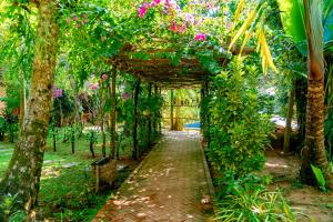 a garden with a wooden arch with pink flowers at La Mer Resort, Phú Quốc in Phú Quốc