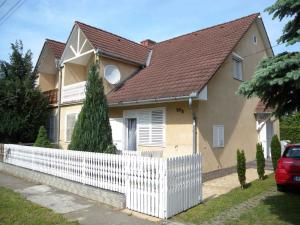 una casa con una cerca blanca delante de ella en Apartments in Balatonkeresztur 37924 en Balatonkeresztúr