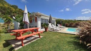 eine rote Picknickbank neben einem Haus mit Pool in der Unterkunft Les Terrasses du Cap in Le Marin