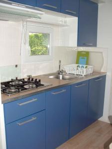 una cucina blu con lavandino e piano cottura di Mobilehomes in Cavallino-Treporti 33773 a Cavallino-Treporti