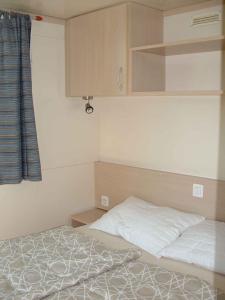 a small bedroom with a bed and a cupboard and a bed at Mobilehomes in Cavallino-Treporti 33773 in Cavallino-Treporti