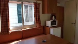 una cucina con divano e una finestra con forno a microonde di Mobilehomes in Cavallino-Treporti 33773 a Cavallino-Treporti