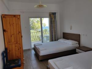 a bedroom with two beds and a window with a balcony at Afroditi Beach in Gerakini