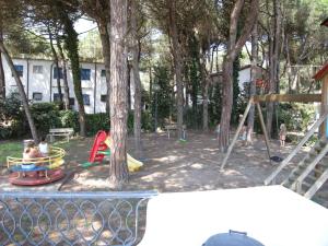 een park met een speeltuin met een boom en schommels bij Apartments in Rosolina Mare 24945 in Rosolina Mare