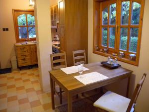 una cucina con tavolo in legno, sedie e finestre di Holiday home in Balatonvilagos 31292 a Balatonvilágos