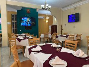 a dining room with tables and chairs and a tv at Hotel San Angel Cerca Del Acuario in Veracruz