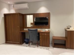 a room with a desk with a television and a chair at فندق كنان سويت in Sulţānah