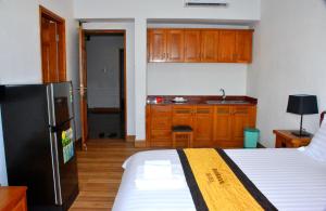 ein Schlafzimmer mit einem Bett und eine Küche mit einem Kühlschrank in der Unterkunft Sun Rose Hotel & Apartment in Xã Thang Tam