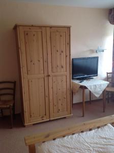 1 dormitorio con TV y un gran armario de madera en Landgasthof zum Wiesengrund, en Hünfeld