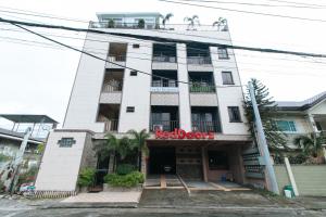een wit gebouw met een rood bordje erop bij RedDoorz Plus at Canley Residential in Manilla