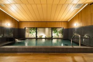 a swimming pool in a building with a wooden ceiling at Hotel Shuranza Chiba in Chiba