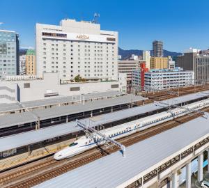 Hotel Associa Shizuoka في شيزوكا: يوجد قطار أبيض على سكة القطار في محطة القطار