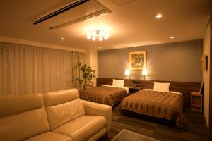 um quarto de hotel com duas camas e um sofá em Sakura Shimanami Hotel em Onomichi
