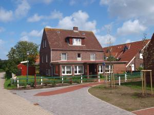 ein großes braunes Haus mit einem Zaun davor in der Unterkunft Pension Friedrich Voss in Langeoog