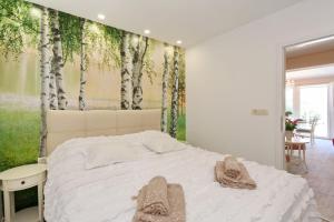 - une chambre dotée d'un lit blanc avec des arbres sur le mur dans l'établissement HACIENDA MIA extra, à Zadar