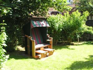 une chaise en bois assise sur l'herbe dans une cour dans l'établissement Pension Friedrich Voss, à Langeoog