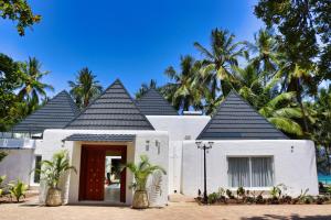 a white house with a red door and palm trees at Searenity Beach Villa in Diani Beach